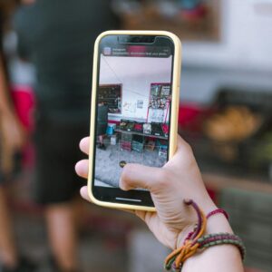 Hand holding smartphone capturing market scene, showcasing technology in everyday life.