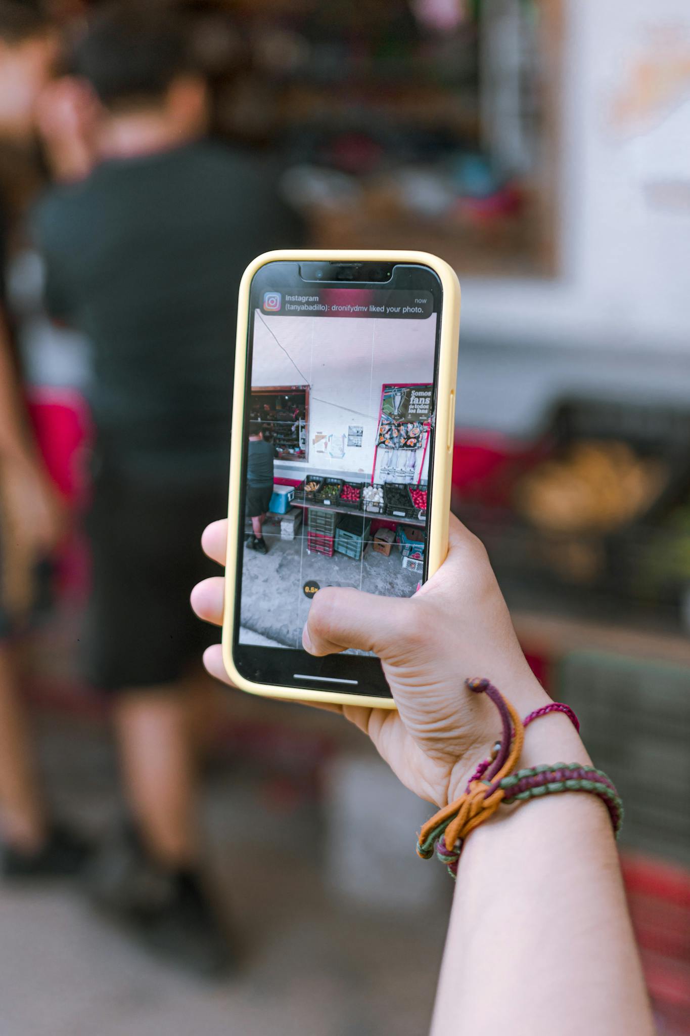 Hand holding smartphone capturing market scene, showcasing technology in everyday life.
